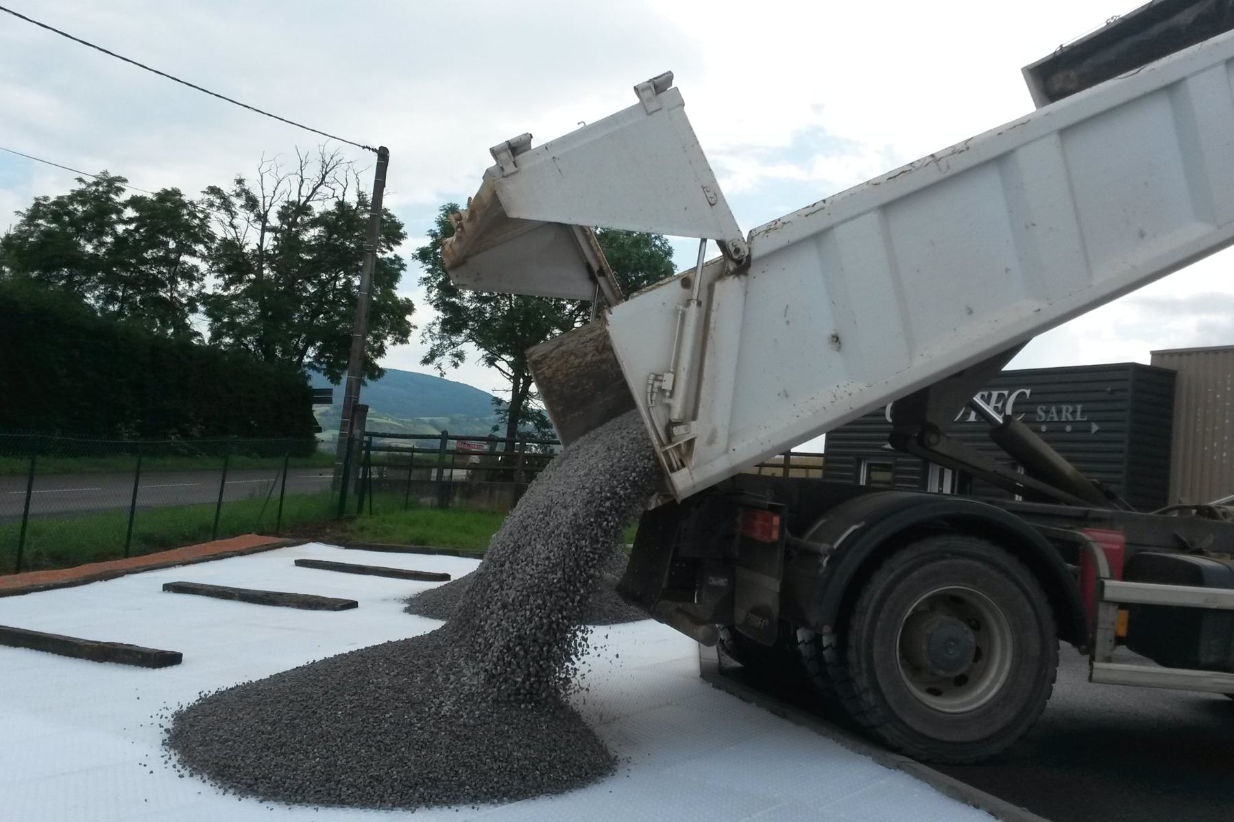 Camion benne vidant du gravier sur une aire de stationnement
