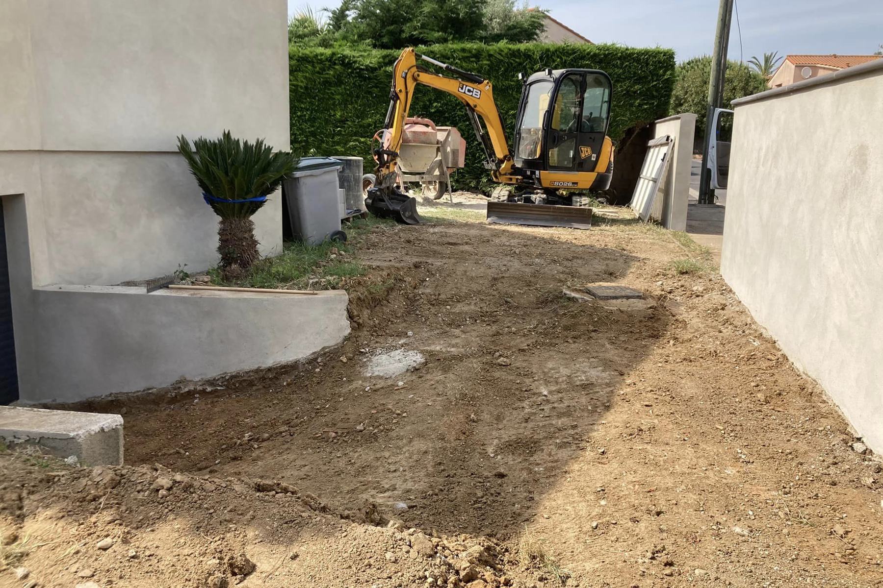 Mini-pelle sur un chantier de décaissement devant une maison